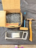 All lot contents overview: nails box, hammer, mallet, hacksaw frame, glass insert clips