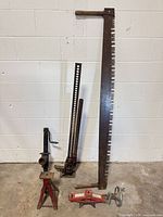 Group shot of high-lift jack, red jack stand, red scissor jack, long crosscut saw