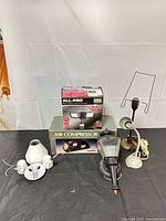Overall view of lot showing boxed compressor, boxed floodlight, lantern, desk lamp and fixture parts