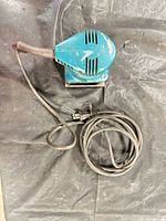 Top view of teal Makita palm sander with attached power cord