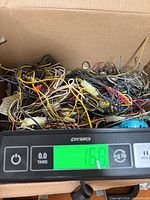 Box of tangled wires and parts on scale showing 16.9 lb