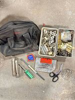 Overall lot showing tool bag, two trays of cabinet hardware, pair handles, tape measure, screwdriver, snips and rods
