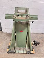 Full front view of green spindle shaper on stand with foot pedal and fence