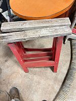 Front view of one red metal folding sawhorse with wood top