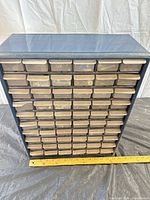 Front view of blue plastic cabinet with 54 drawers and measuring tape for scale