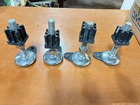 Front view of four adjustable leveling feet standing upright