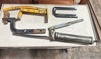 Overview of all items: hitch mount, grease gun, U-bolts, yellow bracket