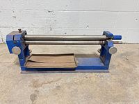 Side view of blue steel slip roller with three rollers and tray