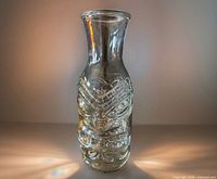 Front view of clear tiki glass vase showing tribal face relief
