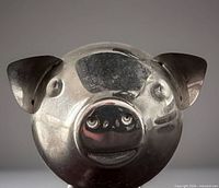 Front view of silver-tone metal piggy bank showing facial features