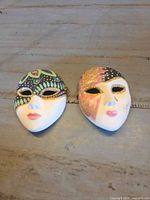 Both ceramic masks side by side on table