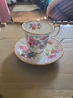Teacup on saucer showing full floral design and gold trim