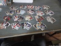 Wide view of multiple piles of hockey cards spread on table with storage box visible