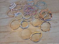 Group of assorted metal bangles and two cuff/rope bracelets on tabletop