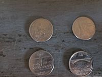 Four quarters showing obverse state designs on flat surface