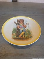 Front view of decorative plate showing full illustration and yellow rim