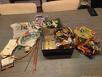 overview of lot on table showing floss bundle, metal tin, hoop, needles, canvases