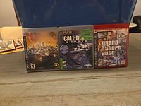 Front view of three PS3 game cases: Need for Speed: Undercover, Call of Duty: Ghosts, Grand Theft Auto IV