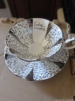 Teacup resting on saucer showing Silver Lace pattern and silver trim