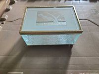 Closed glass jewelry box showing frosted lid with floral design and gold trim