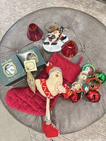 All items arranged on ottoman showing Waterford boxes, votives, plush bird, stocking, bells, metal Santa figurine