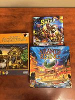 All three boxed games on tabletop: Agricola, Smash Up, Atlantis Rising