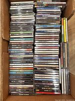 Overview of entire box filled with stacked CD jewel cases showing several album spines