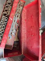 Open red toolboxes showing sockets, wrenches, empty lower chest