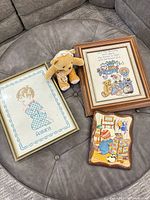 Group view of both framed cross stitches, wooden plaque and plush bear