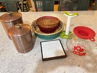 Group shot showing all items in lot: copper canisters, baskets, popcorn maker, corer, trivet