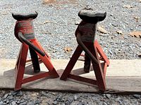 Two red Motomaster 2-ton jack stands on ground showing overall condition