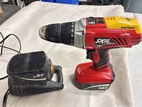 Skil 14.4-V cordless drill on battery beside charger base