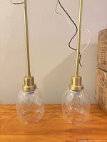 Two assembled pendant lights showing brass rods and faceted clear glass shades