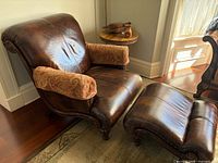 Front angled view of chair and ottoman showing leather, arm covers, and feet