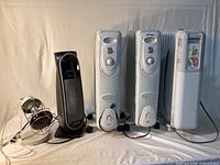 Front view showing all five heaters: three white radiators, black tower heater, small heat-lamp