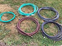 Five coiled garden hoses in various colors and lengths