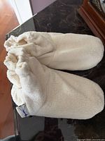 pair of white plush microwaveable slippers on table