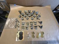 All hardware laid out showing hinges, hooks, plates, braces, felt pads, wood spool and screws