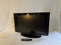 Front view of Samsung 26-inch LCD HDTV on stand with remote placed in front