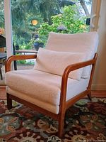 Front perspective view of cream boucle lounge chair showing wood frame and cushions