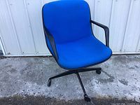 Front three-quarter view of chair showing blue upholstery, black frame and casters