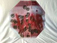 Front of hexagonal sign showing "STOP WAR" text, dents, rust