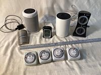 Group shot of all devices including Echo speaker, Deco router, hygrometer, four plug-in timers, dual timer, night light and ruler for scale