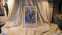 Framed Pike Place Market poster on draped surface showing overall item