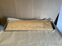 Front view of complete shelf showing wood plank seated between metal end brackets