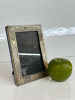 Front view of sterling birth announcement frame beside apple for scale