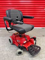 Front three-quarter view of red Pride Go-Chair showing seat, joystick, wheels, and footplate