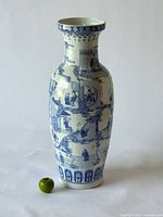 Full view of tall blue and white porcelain floor vase beside apple for scale