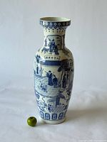 Full view of tall blue and white porcelain floor vase with apple for scale