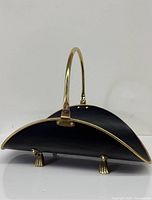 Side view showing curved cradle, brass trim, handle, and two claw feet